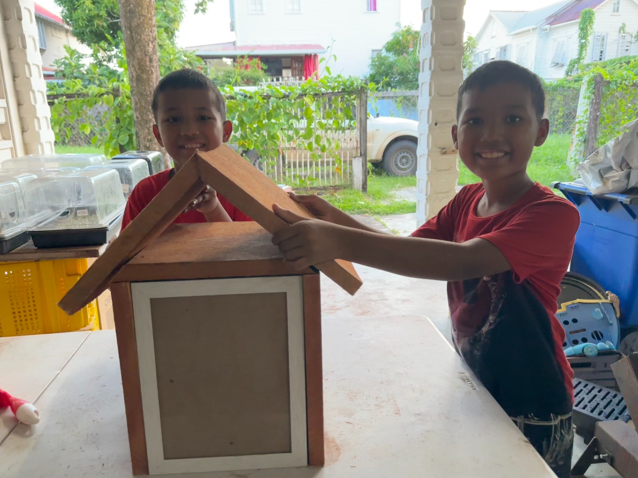 Two boys fitting the roof onto the library cabinet