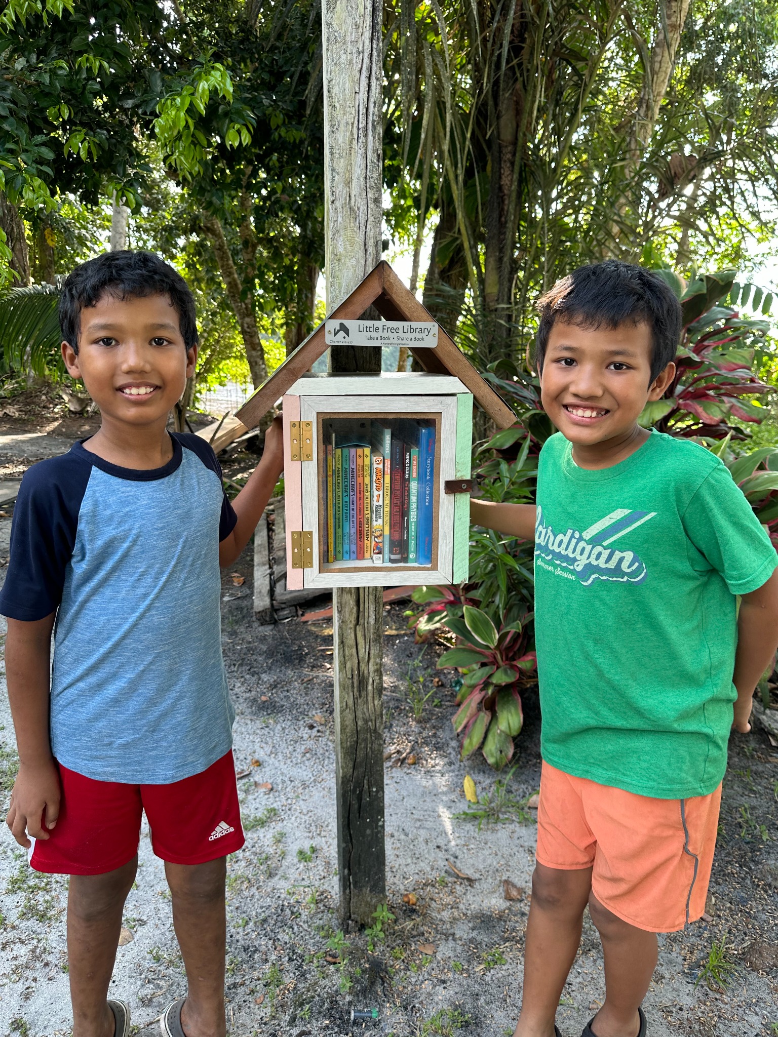 The two young builders standing beside the completed library