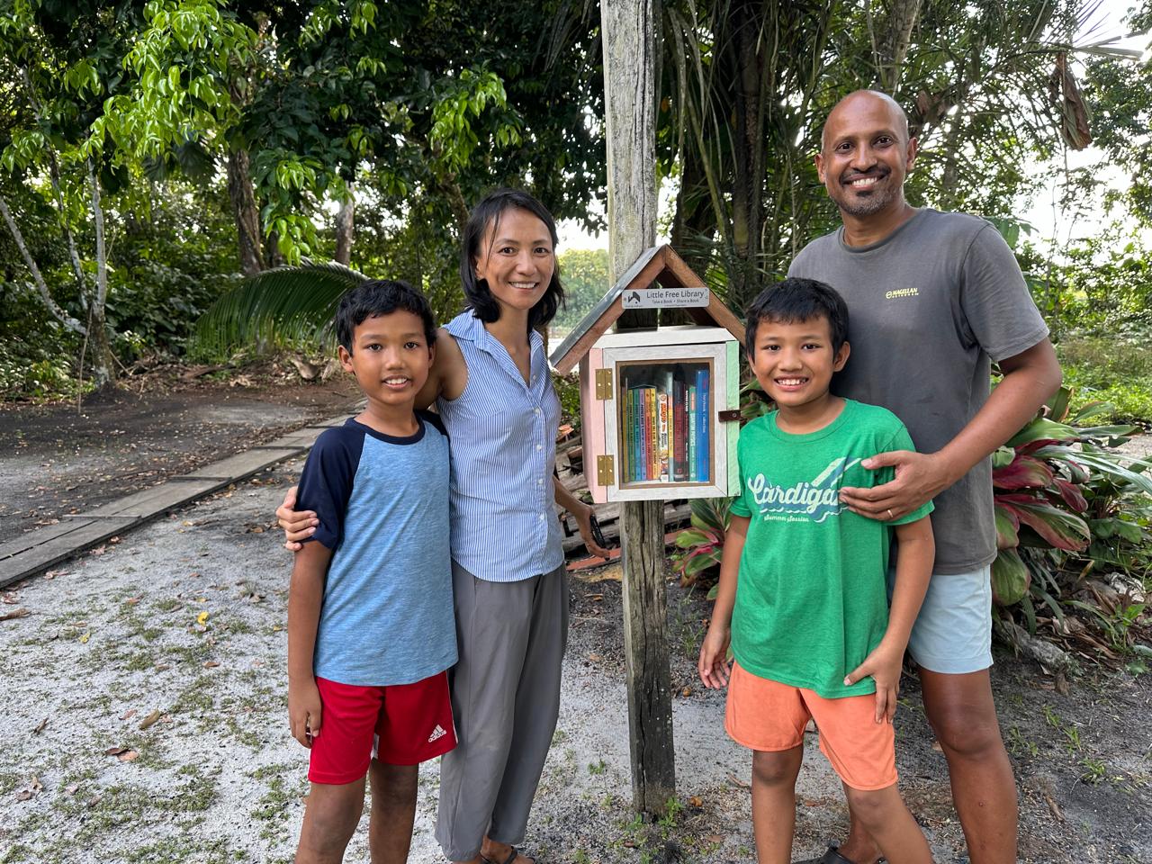 Family standing beside the completed Dora River Landing Little Free Library